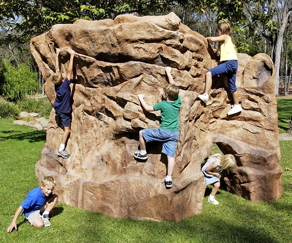kids playing on man made landscape climbing boulder